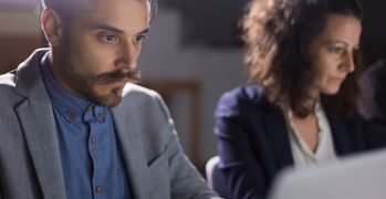 Two colleagues reading from their laptops